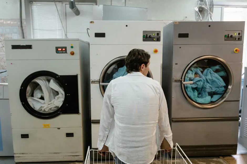 A man uses commercial washing machines at an indoor laundromat.