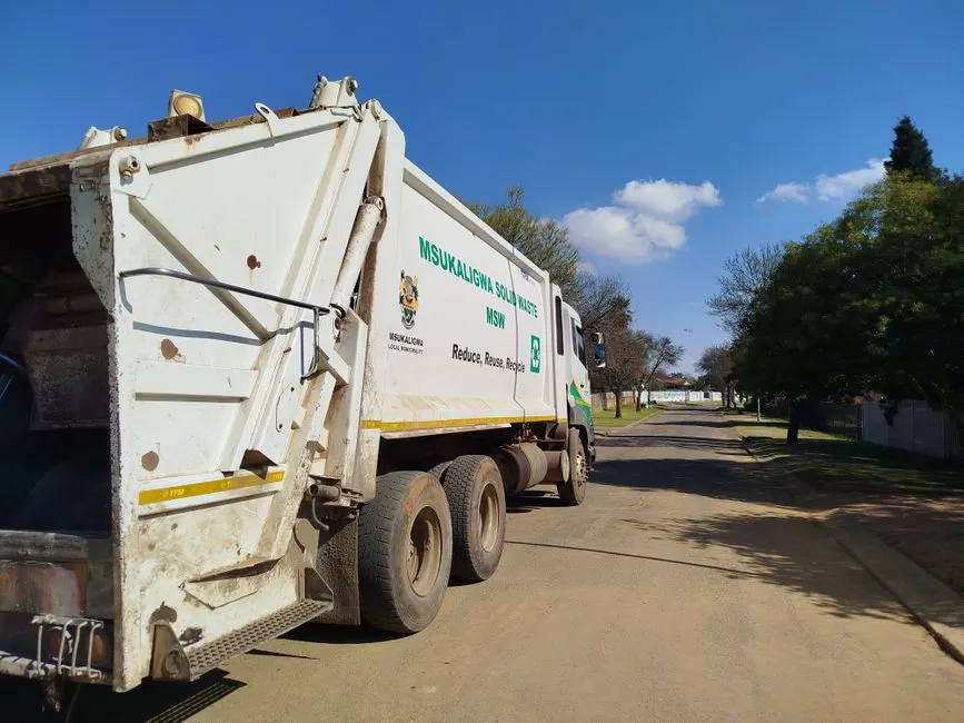 Garbage truck from Msukaligwa municipality collecting waste in a suburban area.